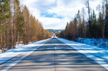 Dağlara giden kış yolu. Asfalt yol ve dağlarda kış manzaralı kar yol kenarında yatar..