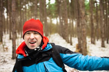 Açık havada giyinmiş mutlu bir adam selfie çekiyor.