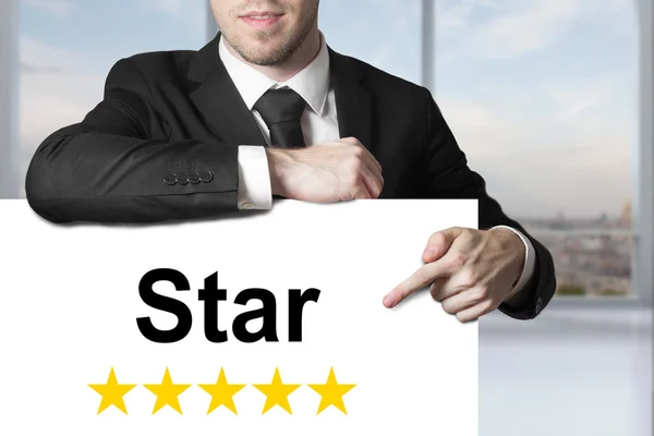 Homem de negócios em terno preto apontando na estrela sinal classificação dourada — Fotografia de Stock
