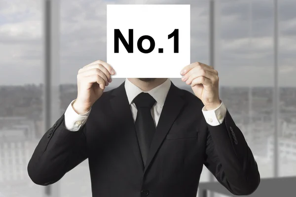 Businessman hiding face behind sign number one — Stock Photo, Image