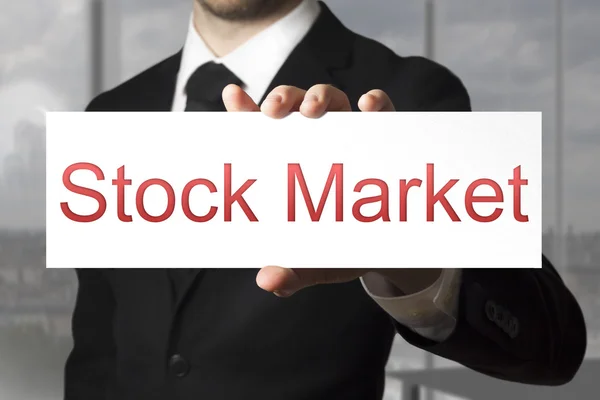 Affärsman hålla tecken aktiemarknaden — Stockfoto