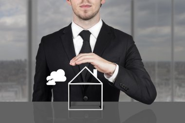 boş bina sembolü üzerinde koruyucu elini tutarak işadamı