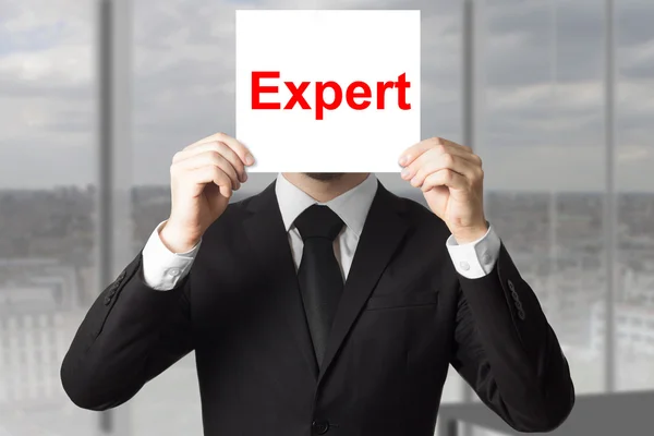 Affärsman som döljer ansiktet bakom tecken expert — Stockfoto