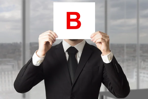 Geschäftsmann im Prozess hält Schild mit Buchstabe b hoch — Stockfoto