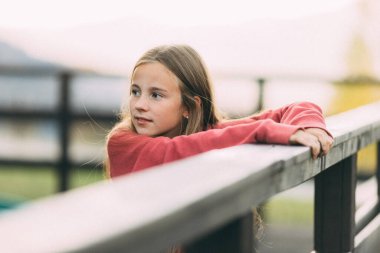 Gün batımında parkta duran genç bir kız. Bir şeye bakan meraklı bir kızın portresi.