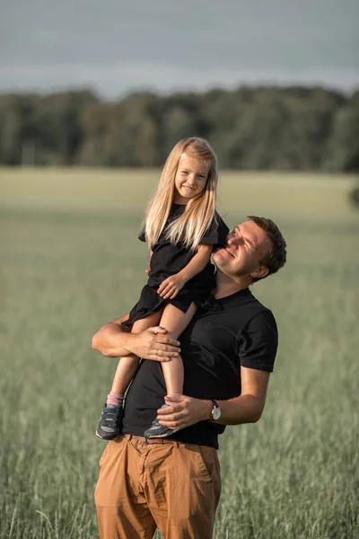 Concepto de crianza y amor. Padre sosteniendo a su pequeña hija en el prado de verano — Foto de Stock
