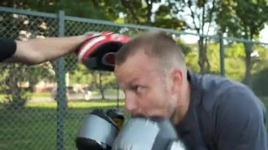 Boks yapıyorum. Beyaz görünümlü genç bir adam antrenmanlarını sokakta yapıyor. Spor ve sağlık