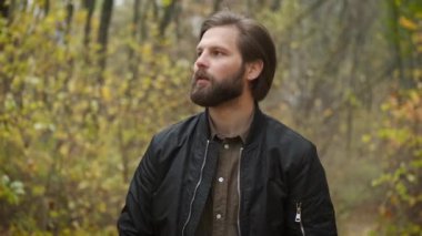 Üzgün sakallı adam parkta yürüyor. Depresyon. Salgın sırasında zor günler ve kendini izole etme