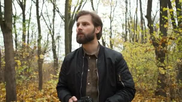 Portrét brutálního fotografa kráčejícího podzimním lesem s fotoaparátem a fotografujícího krajinu zlatého podzimu — Stock video
