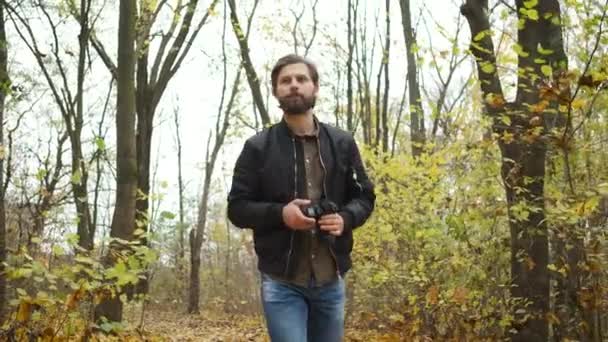 Koncipovaný fotograf kráčející v podzimním lese s fotoaparátem a fotografující krajiny přírody zlatého podzimu — Stock video