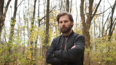 Güz parkında kameraya bakıp saçını düzelten vahşi sakallı beyaz bir adam. Salgın sırasında kendini soyutlama