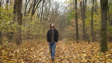 Üzgün sakallı adam parkta yürüyor. Depresyon. Salgın sırasında zor günler ve kendini izole etme