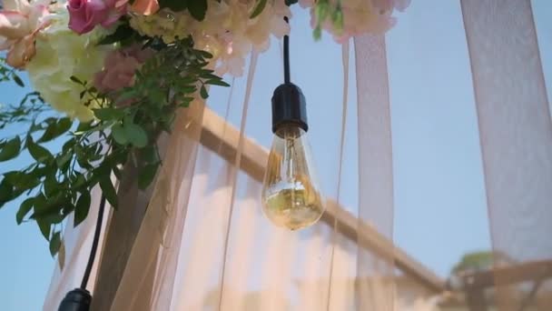 Lámpara. Decoración de la boda. Hermoso arco de boda con flores frescas en el jardín en un día soleado de boda hermoso verano — Vídeos de Stock