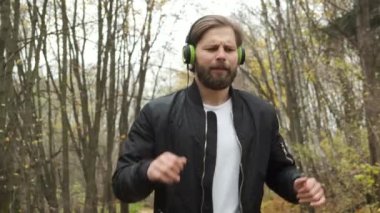 Genç vahşi bir Kafkasyalı, sonbahar parkında duygusal olarak yürüyor ve kulaklıkla müzik dinliyor. Dans ve rahatlama