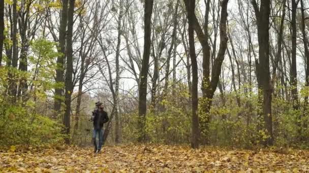 Bedacht fotograaf die met een camera door het herfstbos wandelt en de natuurlijke landschappen van de gouden herfst fotografeert. Onderzoek en uitvinding van inhoud — Stockvideo