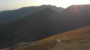 Beyaz elbiseli mutlu bir gelin bir dağın tepesinde ve bir uçurumda duruyor. İnanılmaz doğa ve kel dağlar. Ormanların tahrip edilmesi, ekoloji, sel