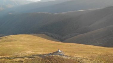 Beyaz elbiseli mutlu bir gelin bir dağın tepesinde ve bir uçurumda duruyor. İnanılmaz doğa ve kel dağlar. Ormanların tahrip edilmesi, ekoloji, sel