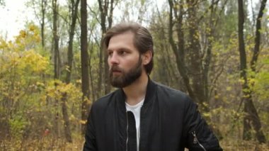 Üzgün sakallı adam parkta yürüyor. Depresyon. Salgın sırasında zor günler ve kendini izole etme