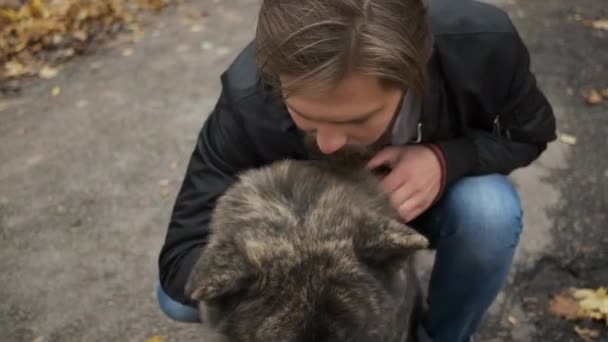 Uomo caucasico che porta a spasso un cane nel parco autunnale. Amore e cura per il cane — Video Stock