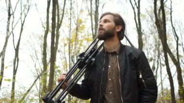 Güz ormanlarında elinde kamera ve tripodla dolaşan ve altın sonbaharın manzaralarını fotoğraflayan vahşi bir fotoğrafçının portresi.