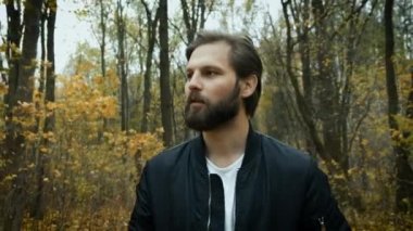 Parkta yürüyen üzgün sakallı adam. Depresyon. Ormandaki açık havada salgın sırasında zor günler ve yalnızlık.