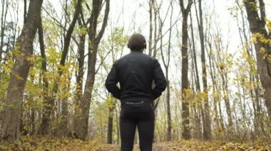 Genç vahşi bir Kafkasyalı, sonbahar parkında duygusal olarak yürüyor ve kulaklıkla müzik dinliyor. Dans ve rahatlama