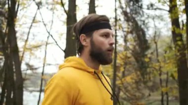 Sonbahar parkında koşan sakallı genç bir adam. Spor ve sağlık