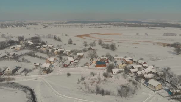 Drönarflyg över den ukrainska snötäckta byn. En vintersaga. Solnedgång i den frostiga vintern — Stockvideo