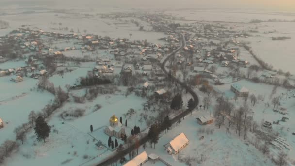 Drohnenflug über dem schneebedeckten ukrainischen Dorf. Ein Wintermärchen. Sonnenuntergang im frostigen Winter — Stockvideo