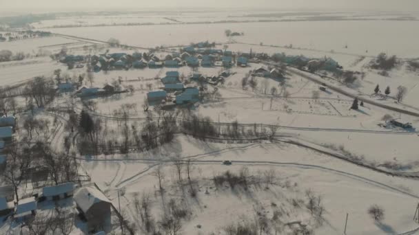 Lot dronem nad ukraińską osadą pokrytą śniegiem. Zimowa bajka. Zachód słońca w mroźną zimę — Wideo stockowe