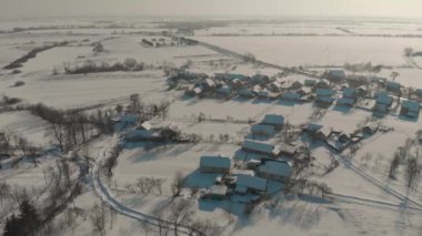 Ukrayna 'nın karla kaplı köyünün üzerinde İHA uçuşu. Bir kış masalı. Soğuk kışta gün batımı