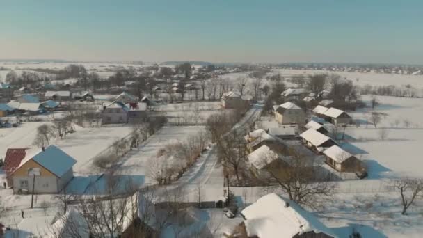 Lot dronem nad ukraińską osadą pokrytą śniegiem. Zimowa bajka. Zachód słońca w mroźną zimę — Wideo stockowe