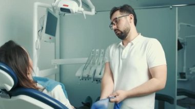 Olars 'taki beyaz dişçi, dişçi koltuğundaki hastayla iletişim kuruyor ve dişi doldurmadan önce mavi eldiven takıyor.