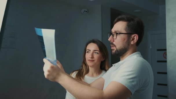 30-year-old dentist man standing talking to brunette patient on sofa and showing tooth x-ray — Stock Video