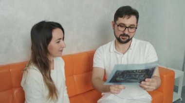 30 yaşında bir dişçi kanepede oturan beyaz bir hastayla konuşuyor ve diş röntgeni çekiyor.
