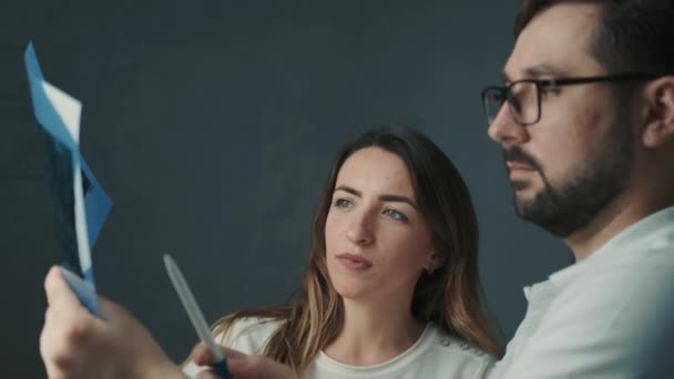 30-year-old dentist man standing talking to brunette patient on sofa and showing tooth x-ray — Stock Video