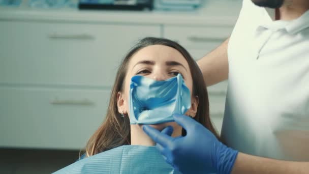 Foto de close-up do rosto de uma paciente sentada em uma cadeira odontológica dentistas. O dentista trata o dente — Vídeo de Stock