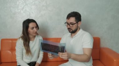 30 yaşında bir dişçi kanepede oturan beyaz bir hastayla konuşuyor ve diş röntgeni çekiyor.
