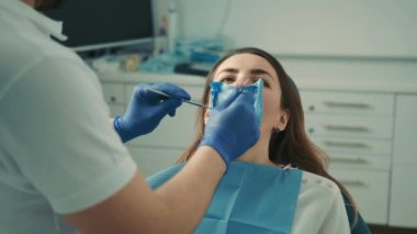Diş hekimi sandalyesinde oturan hasta bir kızın yakın çekim görüntüsü. Diş hekimi dişleri tedavi eder.