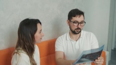 30 yaşında bir dişçi kanepede oturan beyaz bir hastayla konuşuyor ve diş röntgeni çekiyor.