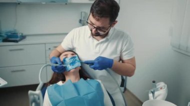 Diş hekimi sandalyesinde oturan hasta bir kızın yakın çekim görüntüsü. Diş hekimi dişleri tedavi eder.