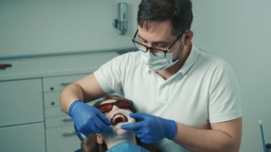Dişçi diş beyazlatma için bir prosedür yapar. Güzel gülümseme. Diş beyazlatma için morötesi lamba