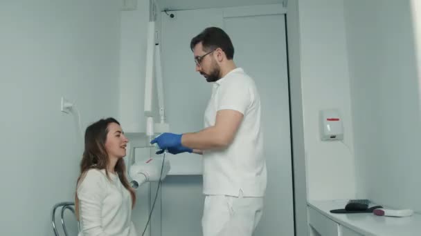 A gloved dentist makes an X-ray of the teeth and shows it to the patient on a digital screen. Dental care — Vídeos de Stock