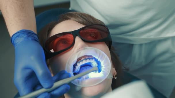 A fogorvos fogfehérítő eljárást végez. Gyönyörű mosoly. Ultraibolya lámpa fogfehérítéshez — Stock videók