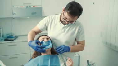 Diş hekimi sandalyesinde oturan hasta bir kızın yakın çekim görüntüsü. Diş hekimi dişleri tedavi eder.