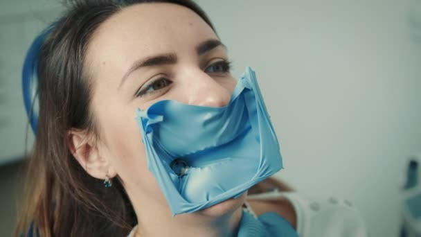 Nahaufnahme des Gesichts einer Patientin, die auf einem Zahnarztstuhl sitzt. Der Zahnarzt behandelt den Zahn — Stockvideo