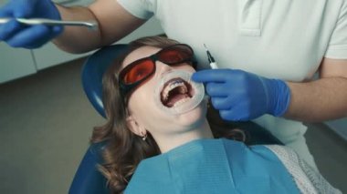 Diş muayenesinden önce ağrı kesici enjekte eden dişçide yatan bir kadının portresi.