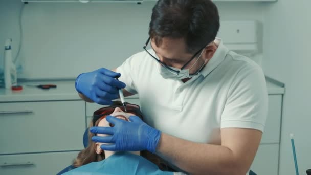Zahnarzt spritzt dem Patienten eine schmerzlindernde Spritze, bevor er den Zahn füllt — Stockvideo