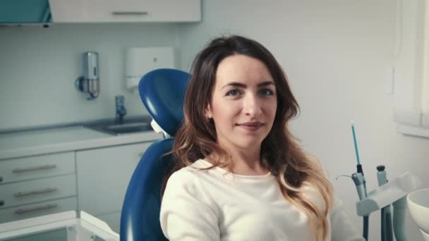 30-letnia kobieta siedzi na krześle dentystycznym i czeka na lekarza. Konsultacje, higiena i piękny uśmiech — Wideo stockowe