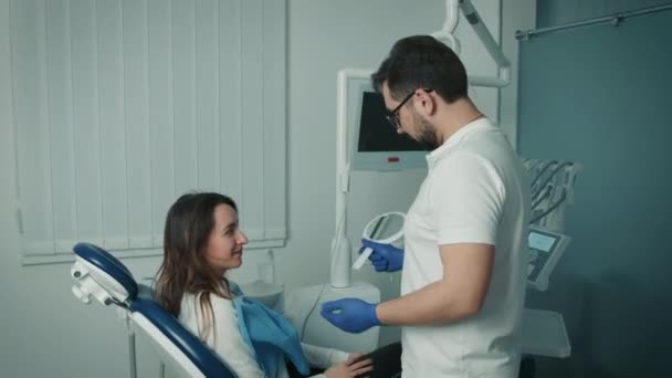 Der Zahnarzt hält dem Patienten einen Spiegel vor. Der Patient ist mit der Arbeit zufrieden — Stockvideo